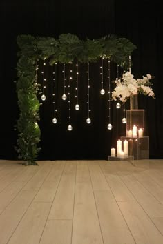 a wedding ceremony with candles, flowers and greenery on the floor in front of a black backdrop