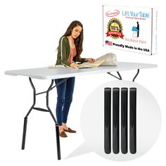 a woman sitting at a table reading a book with three black poles next to it