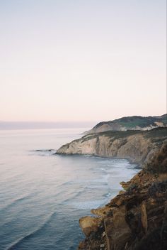 the ocean is calm and blue with waves coming in from the cliffs on either side