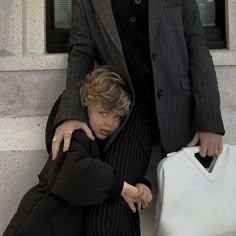 two people standing next to each other in front of a building with a white bag