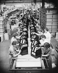 an assembly line with several women working on suitcases in the factory, some holding their hands together and others looking at them