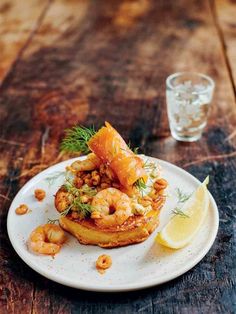 a white plate topped with shrimp and garnish next to a glass of water