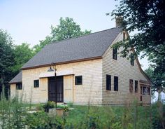 an old house sitting in the middle of a field with tall grass and trees around it