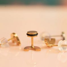 three pairs of gold and black cufflinks on a white surface with one earring in the middle