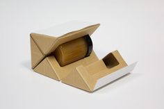 an open cardboard box with a roll of toilet paper in it on a white surface