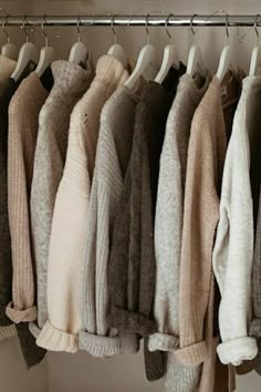 a bunch of sweaters are hanging on a rack