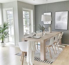 a dining room table with white chairs and pictures on the wall