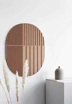 a white vase sitting on top of a table next to a wall mounted wooden panel