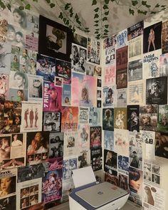 a printer sitting on top of a table in front of a wall covered with posters