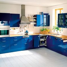 a kitchen with blue cabinets and white tile flooring, including an oven in the center