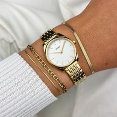 The smallest addition to our bestselling Féroce collection, yet unique in its own way. The CLUSE Féroce Mini watch seamlessly blends minimalism with sleek, pronounced details. With its gold coloured 25 mm round case, white dial and gold coloured 7-link 12 mm strap, this Féroce Mini watch for women will sure make a statement. To adjust the strap we recommend visiting your local jeweler.   True to its name 'Mini', this watch is small. Perfect for those who prefer a petite and subtle timepiece. Watches With Bracelets Women, Golden Watch, Round Watch, Gold Watches Women, Jewelry Essentials, White Dial, Watch Collection