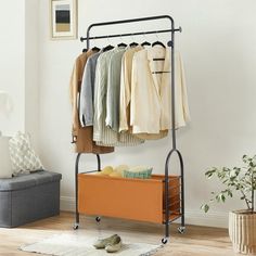 an iron rack with clothes and shoes on it in the corner of a living room