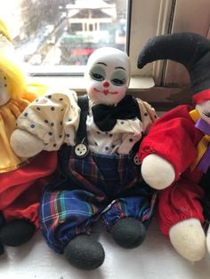 three stuffed clowns sitting next to each other in front of a window sill