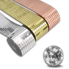 three rolls of shiny disco tape next to a disco ball on a white background,