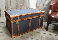 an old trunk sitting on the floor next to a chair