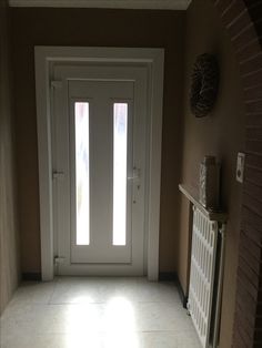 an empty hallway with a white door and tiled floor