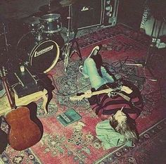 a group of people laying on top of a rug next to guitars and amps