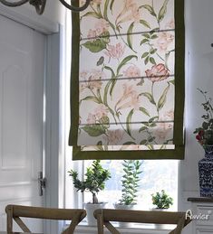 two chairs sitting in front of a window with flowers on the valance and green trim