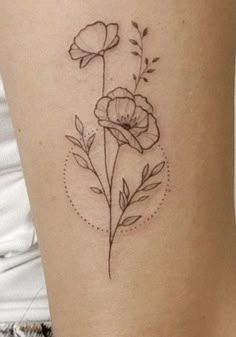 a small flower tattoo on the thigh with leaves and dots around it's petals