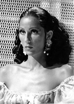 an old photo of a woman with big earrings on her head and wearing a dress