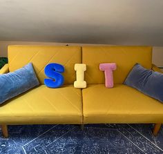 a yellow couch with pillows that spell out the word sit