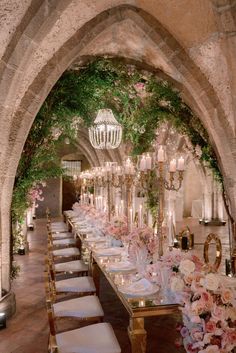 a long table with flowers and candles is set up for a formal function in an archway