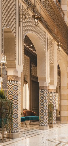 the interior of a large building with intricately decorated walls and columns, along with a blue velvet bench