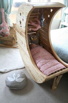 an unusual bed made out of wood with pink sheets and pillows on the bottom half