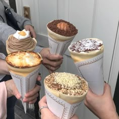 four people holding up ice cream cones with toppings on them and one has an egg in the middle