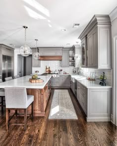 a large kitchen with gray cabinets and white counter tops, an island in the middle