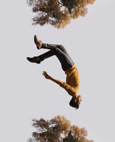 a man flying through the air while riding a skateboard in front of some trees