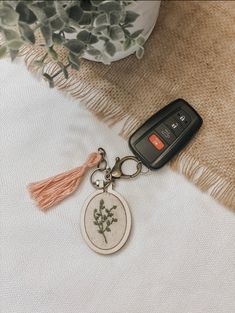 a car keychain with a flower on it sitting next to a potted plant