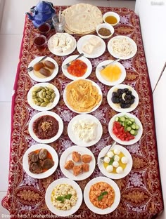 a table topped with plates filled with different types of food and condiments on top of a red cloth