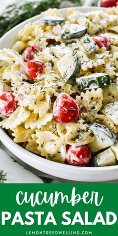 a pasta salad with tomatoes, cheese and herbs in a white bowl