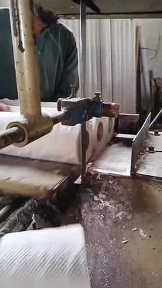 a man working on some kind of machine in a room with lots of white sheets