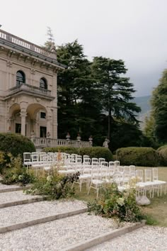 an outdoor wedding venue with white chairs set up on the lawn and steps leading to it