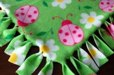 a green blanket with pink ladybugs and daisies on it, sitting on top of a wooden table