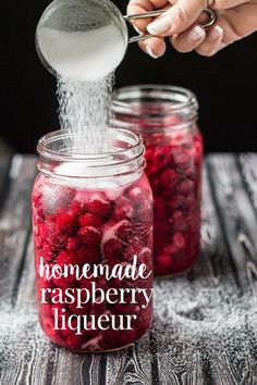 someone sprinkling sugar on raspberries in a jar