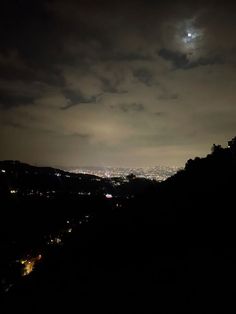 the moon shines brightly in the night sky over a cityscape and hills