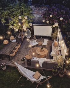 an outdoor deck is lit up with string lights and some hammocks for seating