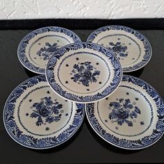 four blue and white plates sitting on top of a black table next to each other