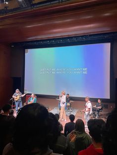 a group of people standing on top of a stage in front of a large screen