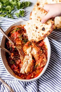 someone is dipping some tortilla bread into a bowl of chicken and tomato soup