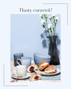 a table topped with pastries next to a vase filled with flowers and two cups