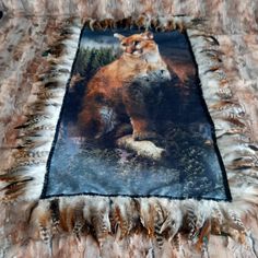 a cat is sitting on top of a blanket that has feathers around it and an animal in the middle