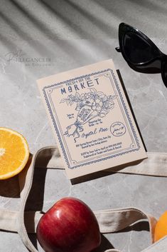 an apple, orange and sunglasses sitting on top of a table next to a book