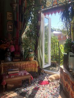 a living room filled with lots of plants next to an open door that leads to a balcony