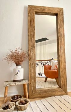 a large mirror sitting on top of a wooden floor next to a vase with flowers