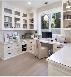 a home office with lots of white cabinets and desks in the middle of it