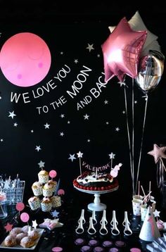 a black and pink party with balloons, cake and desserts on the table for a baby's first birthday